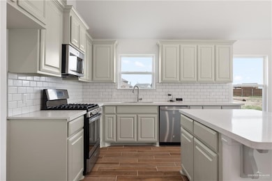 Kitchen featuring appliances with stainless steel finishes, a sink, plenty of natural light, and light countertops