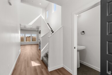 Bathroom featuring healthy amount of natural light, wood finished floors, a towering ceiling, and recessed lighting