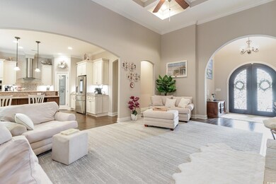 Living area featuring baseboards, arched walkways, ornamental molding, a ceiling fan, and french doors