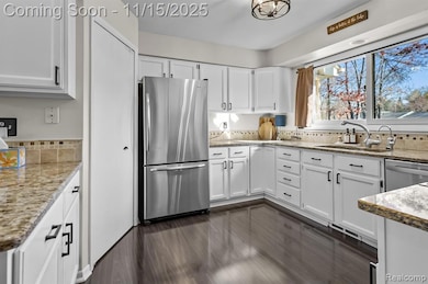 Kitchen featuring white cabinetry, appliances with stainless steel finishes, light stone countertops, and backsplash