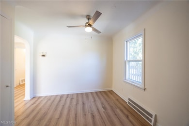 Spare room featuring wood finished floors, ceiling fan, and arched walkways