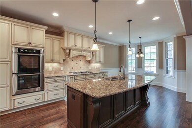 Wonderful Kitchen with large contrasting work Island, Double Oven, Custom tile backsplash, decorative range hood, and upgraded appliances.