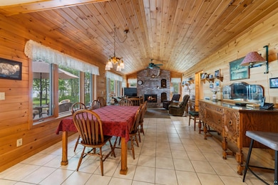 Dining room featuring wood walls, vaulted ceiling, a fireplace, light tile patterned floors, and a chandelier