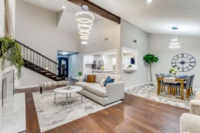 Living area with stairs, beam ceiling, wood finished floors, and high vaulted ceiling