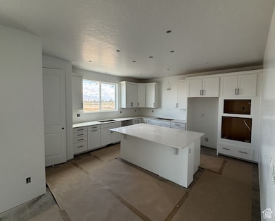Kitchen featuring white cabinets, a kitchen bar, a center island, and light stone counters
