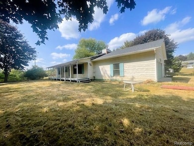 Back of house with covered porch, a lawn, and a chimney