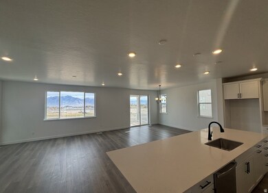 Kitchen with white cabinetry, a center island with sink, dark wood finished floors, open floor plan, and a chandelier