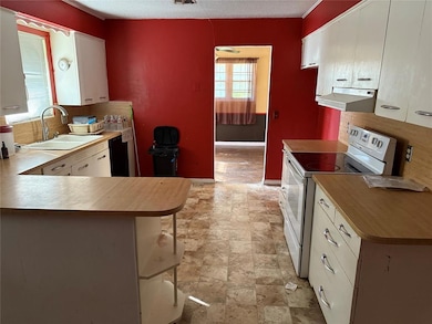 Kitchen featuring white electric range oven, light countertops, range hood, white cabinets, and stone finish flooring