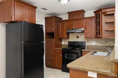 Kitchen featuring black appliances, sink, kitchen peninsula, and decorative backsplash