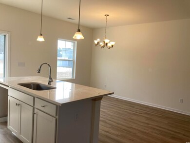 Kitchen featuring a sink, baseboards, hanging ligh