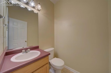 Half bathroom with toilet, vanity, and tile patter