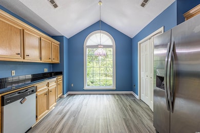 Kitchen with visible vents, appliances with stainless steel finishes, wood finished floors, and vaulted ceiling