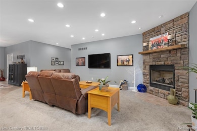 Living room featuring recessed lighting, a stone fireplace, and light colored carpet