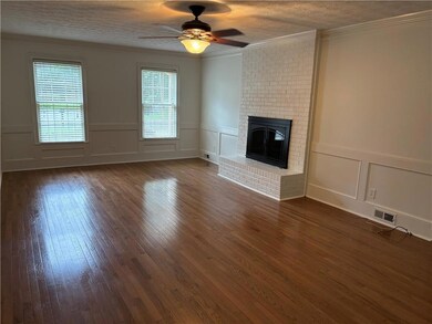 Unfurnished living room with a decorative wall, healthy amount of natural light, a fireplace, crown molding, and dark wood-type flooring