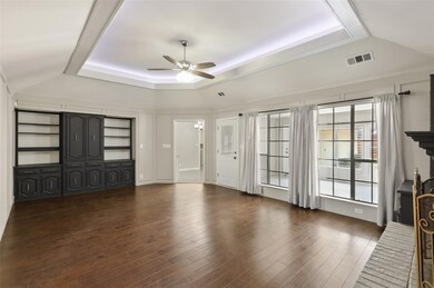 Unfurnished living room with a tray ceiling, dark wood finished floors, and a ceiling fan