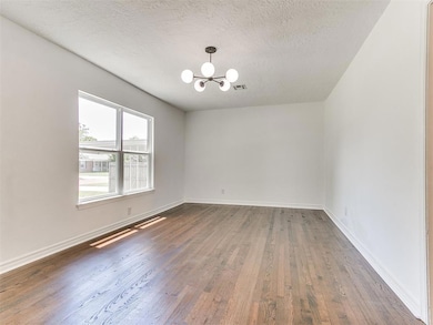 Bright and airy living room with updated lighting and refinished wood floors.