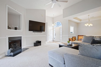 Living area with carpet flooring, a chandelier, a fireplace, and a ceiling fan