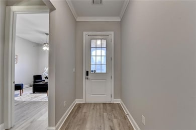 Entryway featuring crown molding, ceiling fan, and wood finished floors