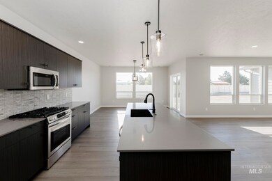 Kitchen with stainless steel appliances, a kitchen island with sink, decorative light fixtures, modern cabinets, and decorative backsplash