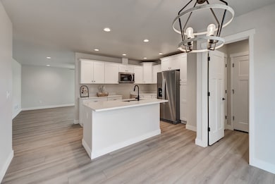 Kitchen featuring white cabinets, stainless steel appliances, recessed lighting, an island with sink, and a chandelier