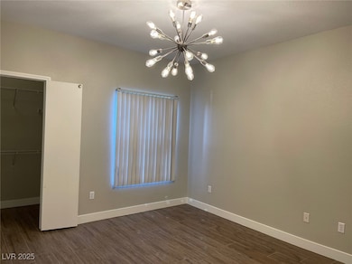 Unfurnished bedroom featuring a walk in closet, dark wood-type flooring, and a chandelier