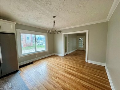 Unfurnished dining area featuring crown molding, baseboards, a chandelier, a textured ceiling, and light wood-style floors