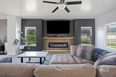 Carpeted living area with a ceiling fan and a glass covered fireplace