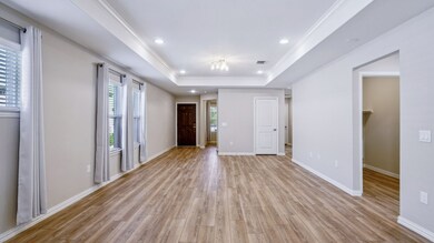 Empty room featuring light wood-type flooring, a raised ceiling, crown molding, and recessed lighting