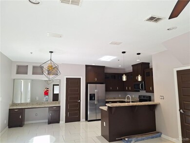 Kitchen featuring kitchen peninsula, stainless steel appliances, light tile patterned flooring, and decorative light fixtures