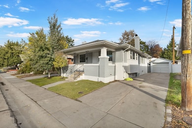 Bungalow-style house with a chimney, an outbuilding, covered porch, driveway, and a front yard