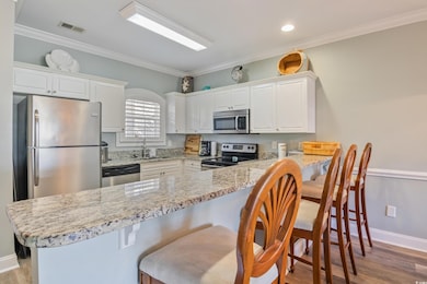 Kitchen with visible vents, a sink, white cabinetry, stainless steel appliances, and a peninsula