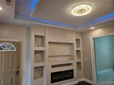 Unfurnished living room with a tray ceiling, built