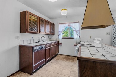 Kitchen with exhaust hood, sink, tile counters, di
