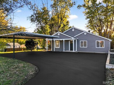 View of front of house with asphalt driveway and a detached carport