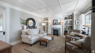 Living area with a tiled fireplace, light wood-style floors, and coffered ceiling