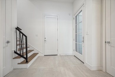 The proper foyer, with soaring 11’ ceilings, highlights design details from the custom iron railing to the sophisticated multi-piece trim.  The door to the left leads to a spacious closet and conceals the elevator shaft that services all floors.