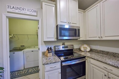 Laundry room off the kitchen, washer and dryer with shelving and room to hang laundry. 