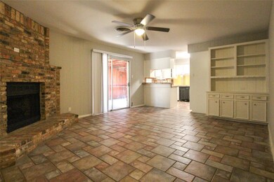Family Room offers a Brick fireplace, tile flooring, shelf & cabinet built-in and ceiling fan w/ light.