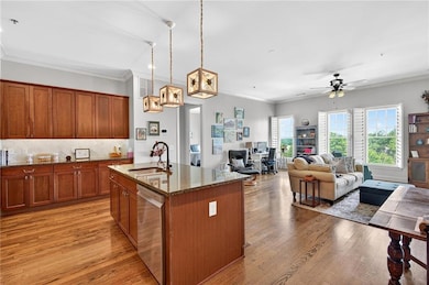 Kitchen with stainless steel appliances, crown molding, dark stone countertops, light wood finished floors, and brown cabinets