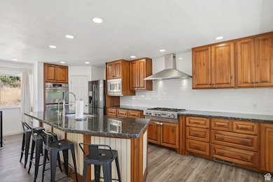 Kitchen featuring wood finished floors, brown cabinets, decorative backsplash, stainless steel appliances, and recessed lighting