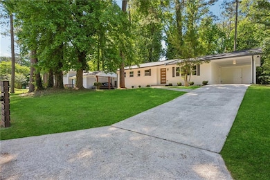 Single story home with driveway, a front yard, and a carport