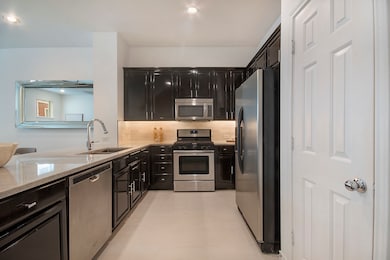 Main level kitchen featuring dark cabinetry, stainless steel appliances, taj mahal quartzite counters, backsplash, and recessed lighting