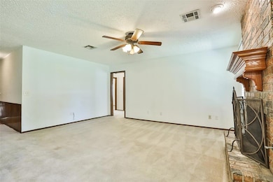 Unfurnished living room with a ceiling fan, a textured ceiling, a brick fireplace, carpet floors, and baseboards