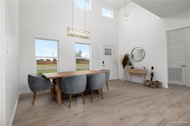 Dining room with a notable chandelier, light hardwood / wood-style floors, and a towering ceiling