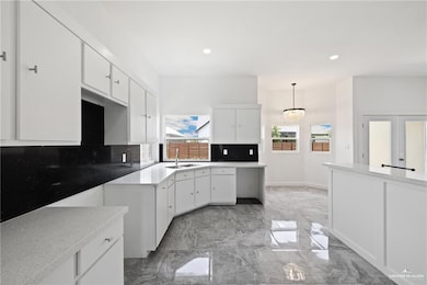 Kitchen with backsplash, white cabinetry, light marble finish floors, recessed lighting, and decorative light fixtures