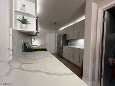 Kitchen featuring gray cabinetry, open shelves, li