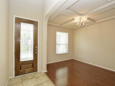 Entryway featuring coffered ceiling, a chandelier, wood finished floors, beam ceiling, and arched walkways
