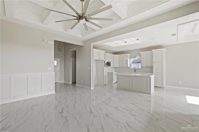 Unfurnished living room featuring coffered ceiling, a ceiling fan, light marble finish flooring, a sink, and baseboards