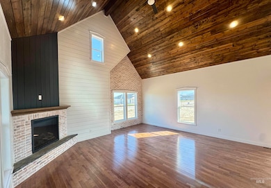 Unfurnished living room featuring plenty of natural light, a wooden ceiling with exposed beams, dark wood finished floors, a fireplace, and wood walls