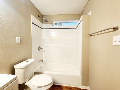 Full bath with a textured wall, shower / bath combination, vanity, and dark wood-style floors